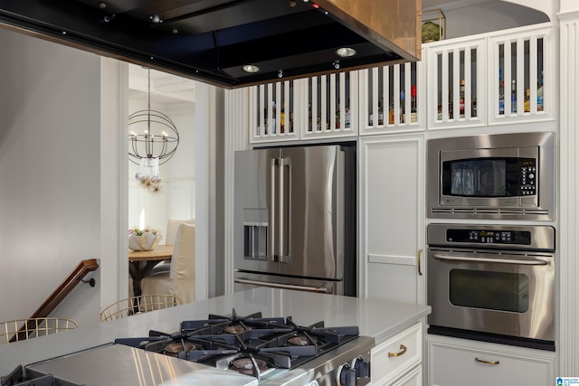 kitchen with ventilation hood, white cabinetry, stainless steel appliances, and an inviting chandelier