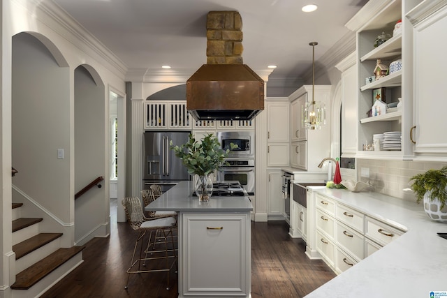 kitchen with appliances with stainless steel finishes, dark wood-type flooring, sink, decorative light fixtures, and a kitchen island