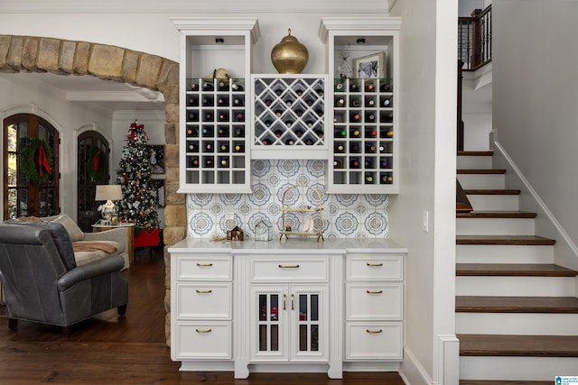 bar featuring white cabinets, crown molding, and dark wood-type flooring