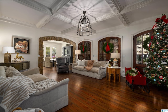 living room with dark wood-type flooring, coffered ceiling, ornamental molding, a notable chandelier, and beam ceiling