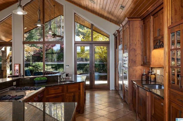 kitchen with dark stone counters, french doors, sink, hanging light fixtures, and wood ceiling