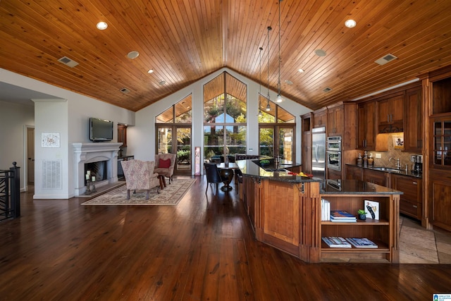 kitchen featuring decorative light fixtures, a center island, dark wood-type flooring, and stainless steel appliances