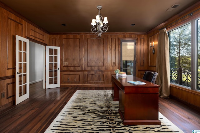 office with french doors, dark hardwood / wood-style flooring, wooden walls, and a notable chandelier