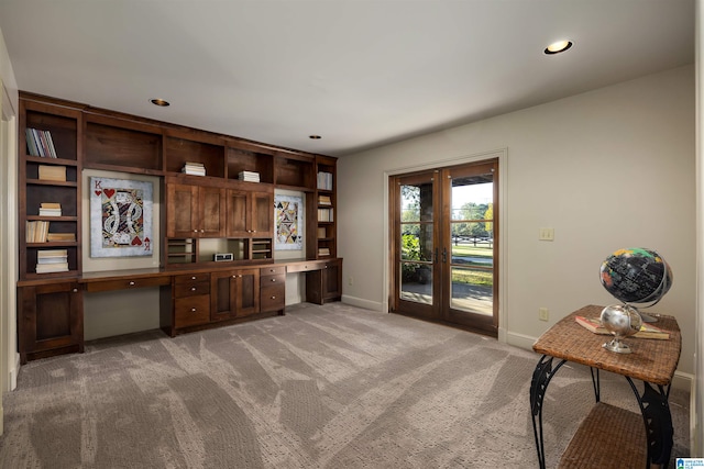 carpeted office space with built in desk and french doors