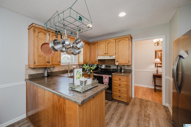 kitchen featuring sink, kitchen peninsula, a textured ceiling, wood-type flooring, and stainless steel appliances