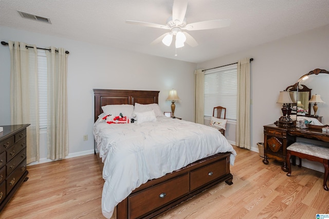 bedroom with a textured ceiling, light hardwood / wood-style flooring, and ceiling fan