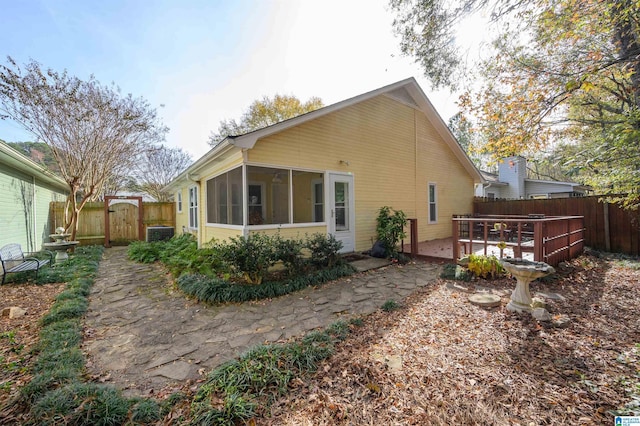 back of house with a wooden deck, a sunroom, and a patio