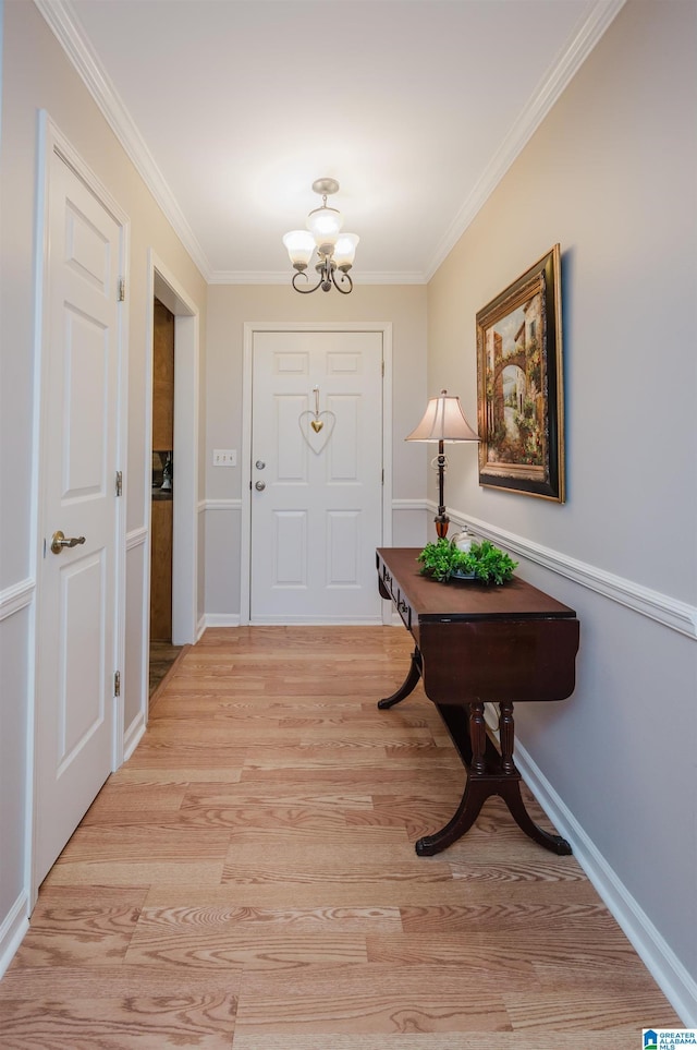 foyer entrance featuring light hardwood / wood-style floors, ornamental molding, and an inviting chandelier