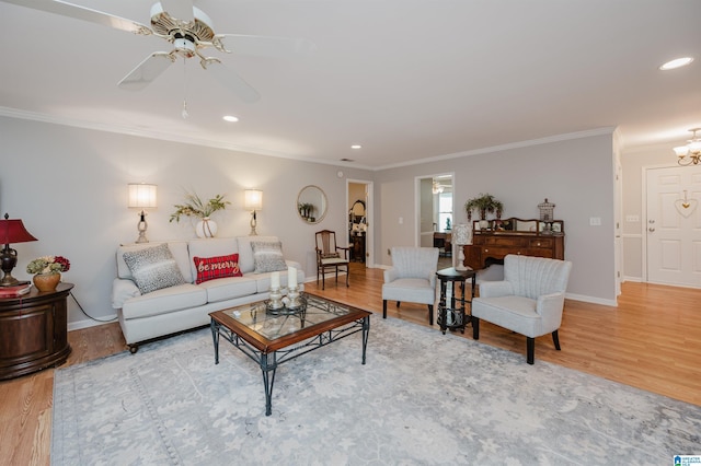 living room with wood-type flooring, ceiling fan with notable chandelier, and ornamental molding