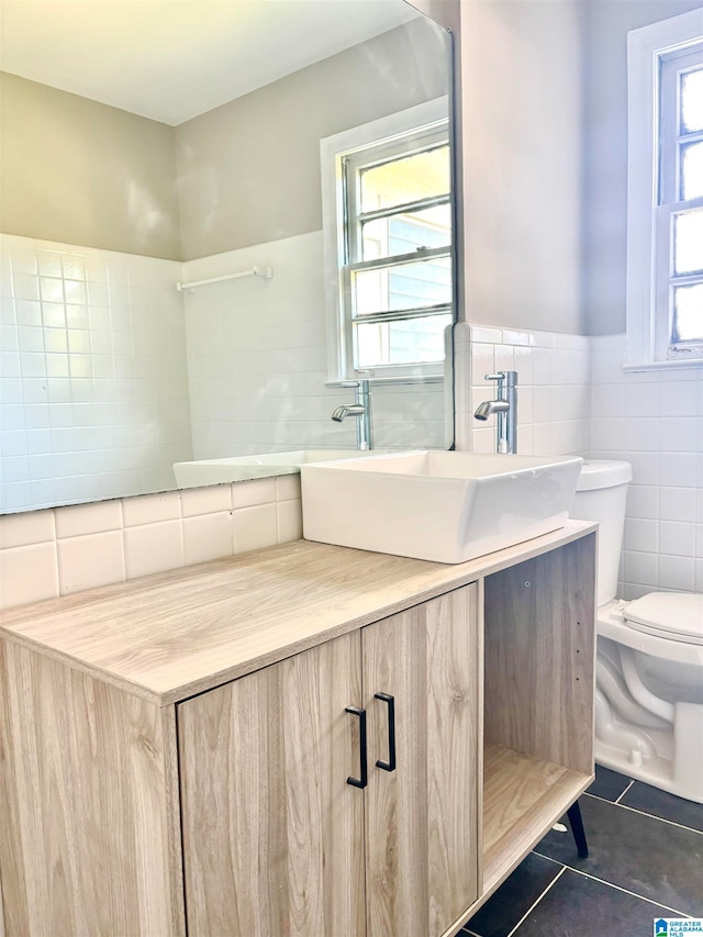 bathroom featuring tile patterned flooring, vanity, toilet, and tile walls