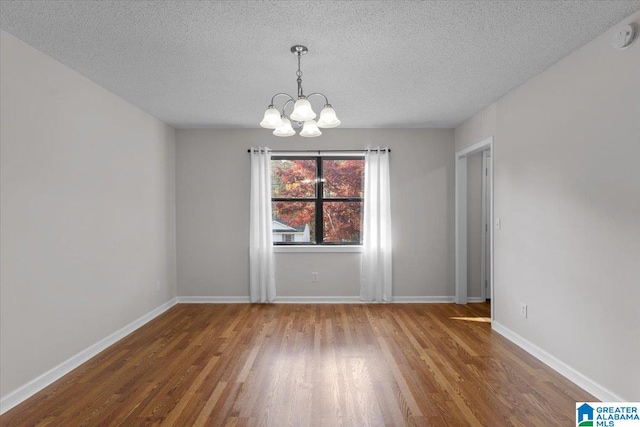 spare room featuring hardwood / wood-style floors, a chandelier, and a textured ceiling