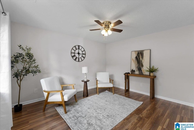 living area with ceiling fan, dark wood-type flooring, and a textured ceiling