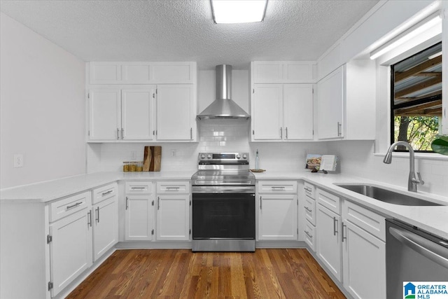 kitchen with white cabinetry, sink, wall chimney exhaust hood, dark hardwood / wood-style flooring, and appliances with stainless steel finishes