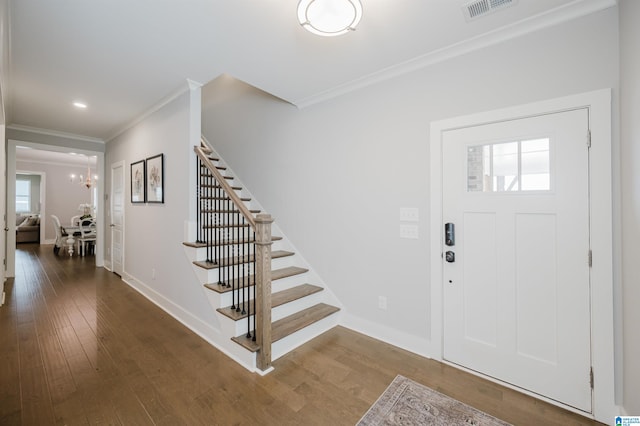 foyer with wood-type flooring, an inviting chandelier, and crown molding