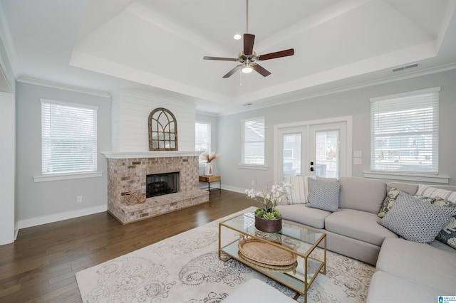 living room with a tray ceiling, a fireplace, ceiling fan, and dark hardwood / wood-style flooring