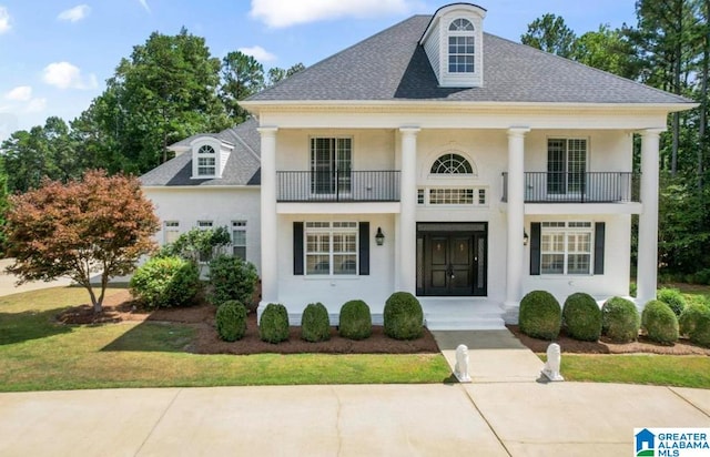 neoclassical / greek revival house featuring a balcony and a front lawn