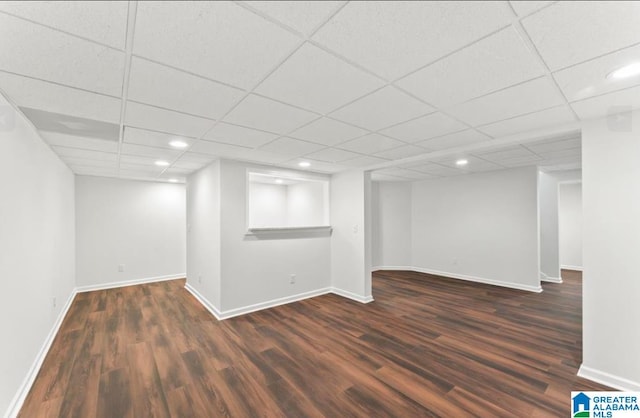 basement with a drop ceiling and dark hardwood / wood-style flooring