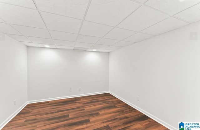 basement featuring a drop ceiling and dark wood-type flooring