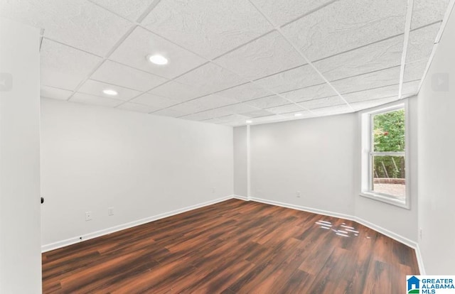 spare room featuring a paneled ceiling and dark hardwood / wood-style floors