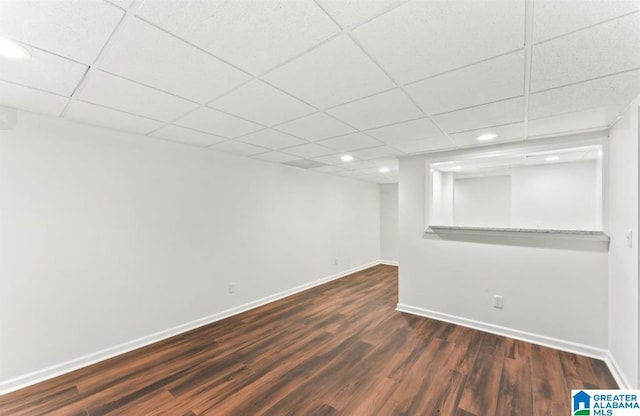 basement with a paneled ceiling and dark hardwood / wood-style floors