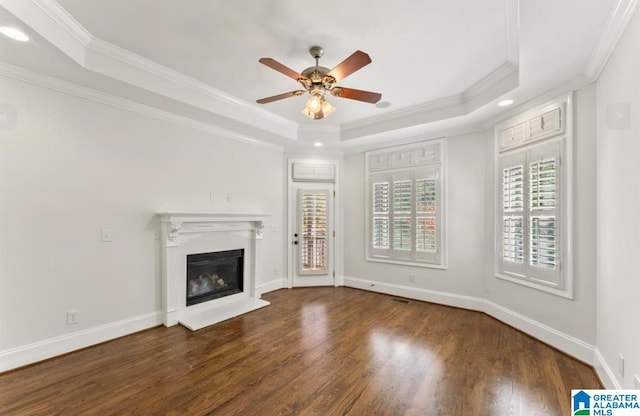 unfurnished living room with ceiling fan, a raised ceiling, ornamental molding, and dark wood-type flooring