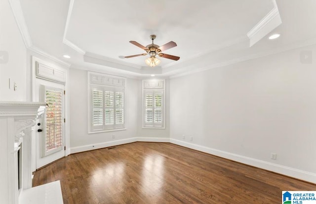 unfurnished living room with a tray ceiling, a wealth of natural light, ceiling fan, and wood-type flooring