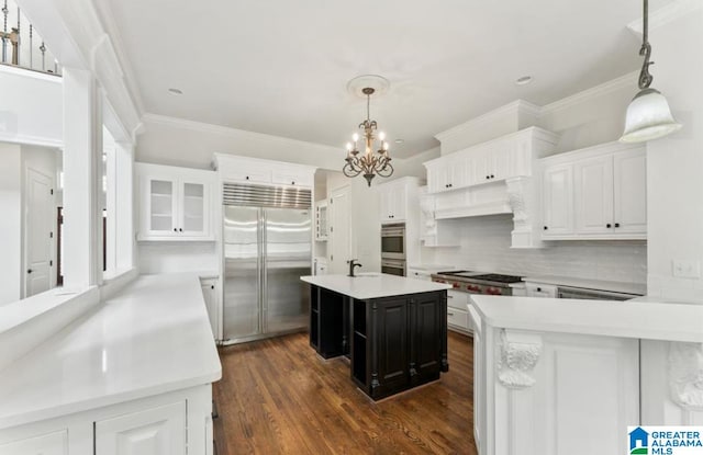 kitchen with built in fridge, a center island, white cabinetry, and pendant lighting