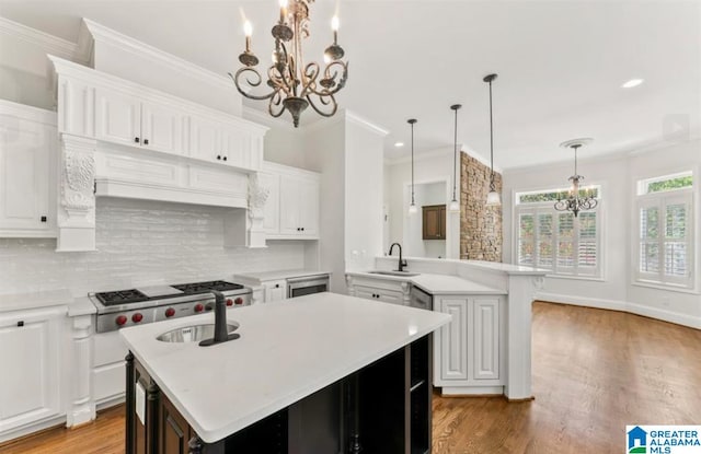 kitchen featuring white cabinetry, sink, kitchen peninsula, an island with sink, and light wood-type flooring