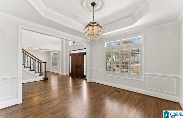 foyer featuring a notable chandelier, dark hardwood / wood-style floors, a raised ceiling, and crown molding