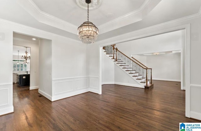 unfurnished room with a raised ceiling, ornamental molding, dark wood-type flooring, and a chandelier