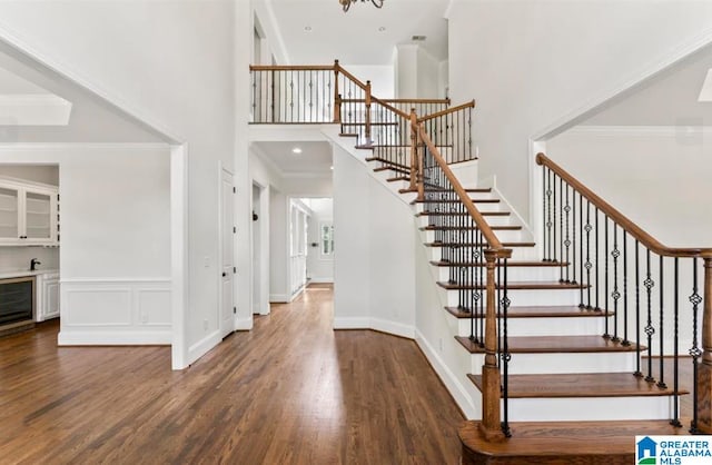 stairway with hardwood / wood-style flooring, a notable chandelier, a towering ceiling, and crown molding