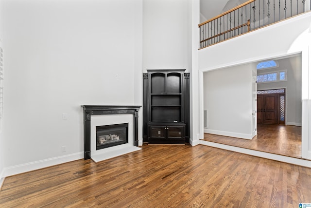 unfurnished living room with hardwood / wood-style flooring and a towering ceiling