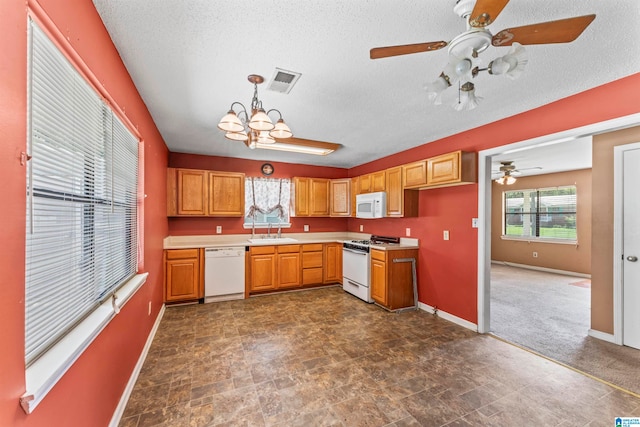 kitchen with a textured ceiling, white appliances, sink, pendant lighting, and an inviting chandelier