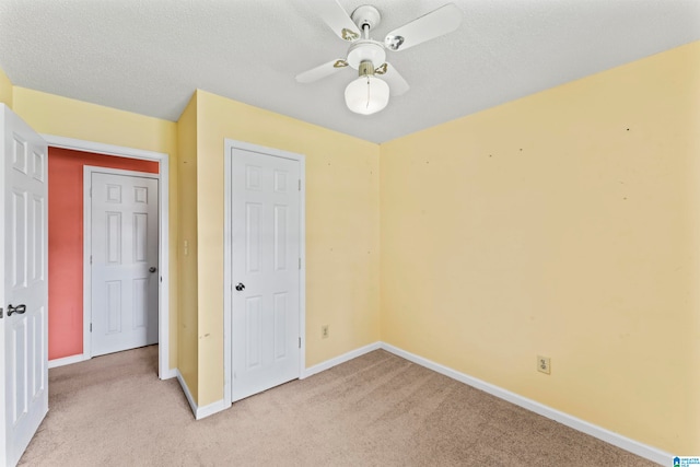 unfurnished bedroom with ceiling fan, light colored carpet, and a textured ceiling