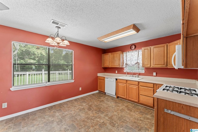 kitchen featuring white appliances, an inviting chandelier, sink, a textured ceiling, and decorative light fixtures