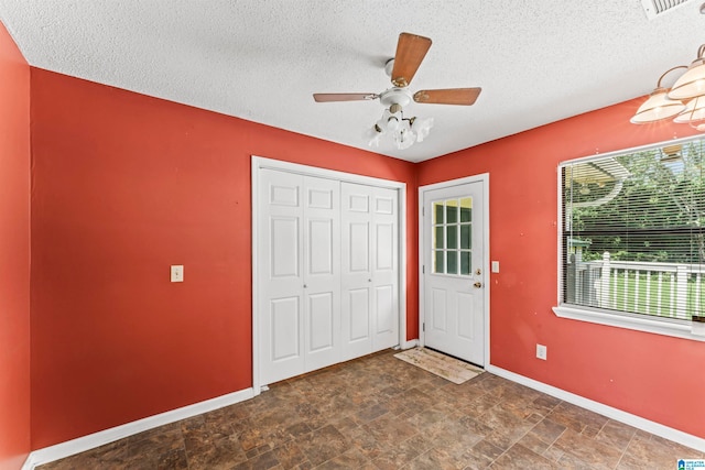 interior space with a textured ceiling and ceiling fan