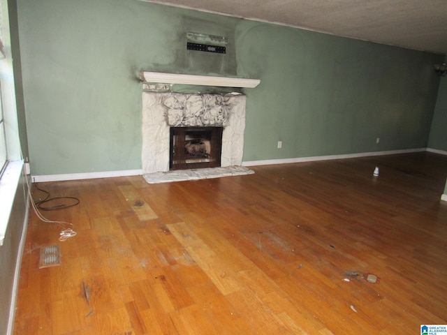 unfurnished living room with a stone fireplace and wood-type flooring