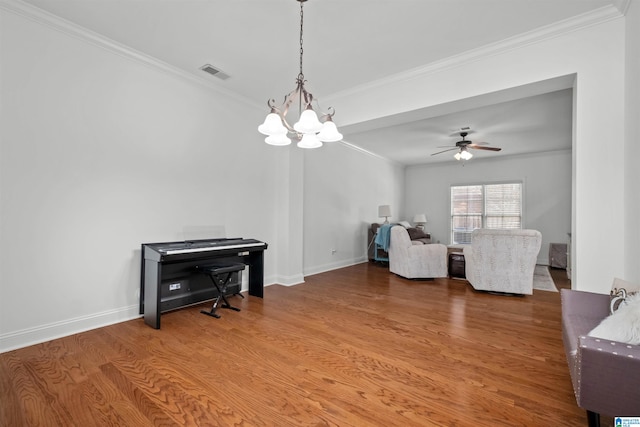 sitting room featuring wood-type flooring, ceiling fan with notable chandelier, and crown molding