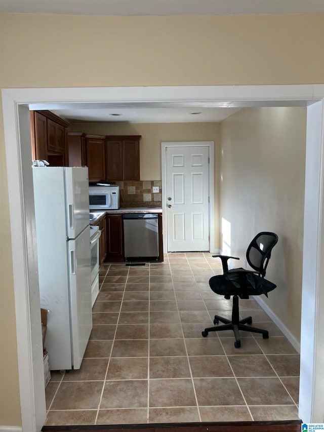 kitchen with decorative backsplash, dark tile patterned flooring, and white appliances