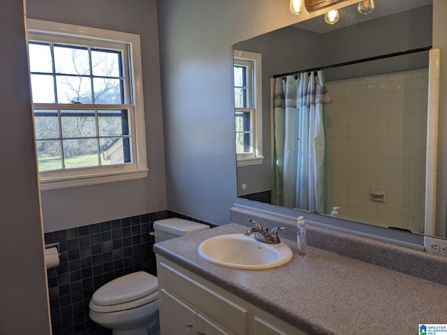 bathroom featuring toilet, vanity, tile walls, and walk in shower