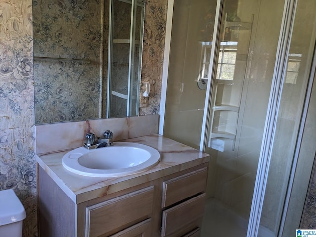 bathroom with a shower with door, vanity, and toilet