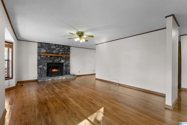 unfurnished living room featuring ceiling fan, a fireplace, wood-type flooring, and a textured ceiling