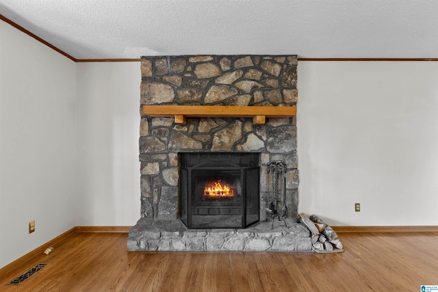 interior details with a textured ceiling, crown molding, wood-type flooring, and a fireplace