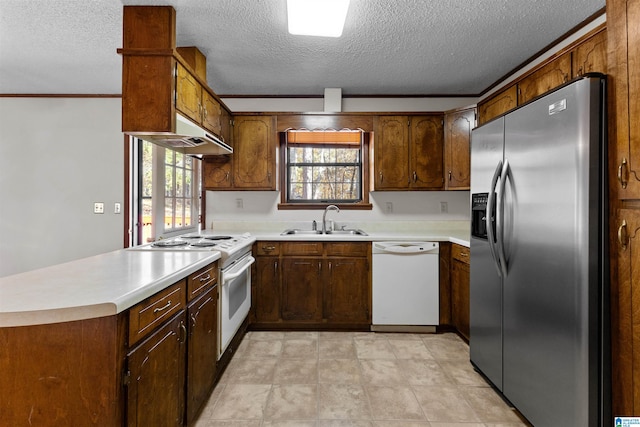 kitchen featuring a textured ceiling, kitchen peninsula, white appliances, and sink