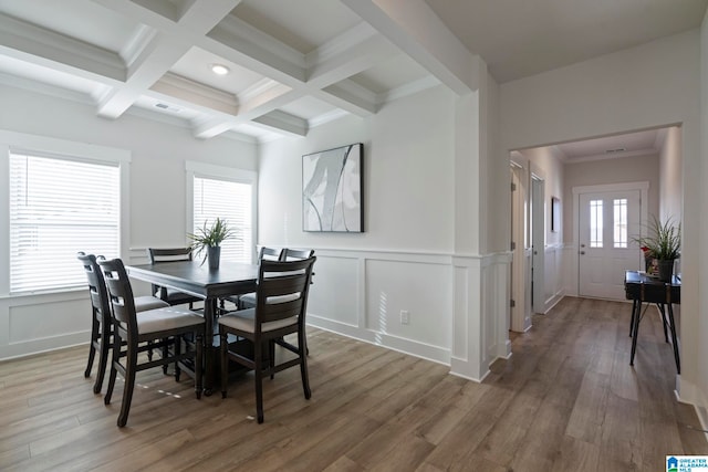 dining area with beamed ceiling, wood-type flooring, ornamental molding, and coffered ceiling