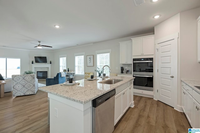 kitchen with a high end fireplace, sink, an island with sink, appliances with stainless steel finishes, and white cabinetry