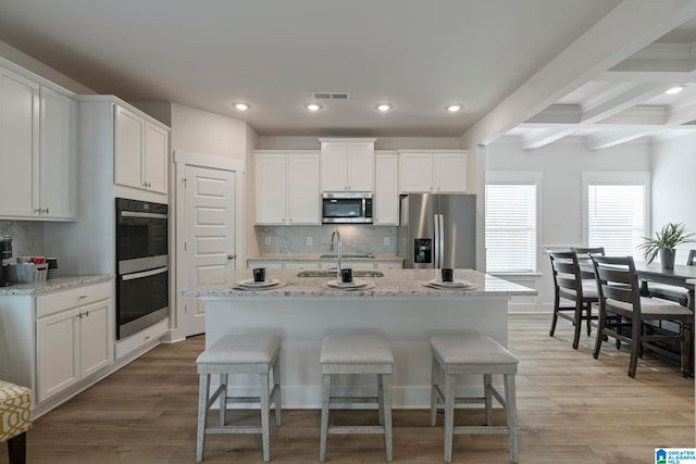 kitchen with a center island with sink, white cabinetry, and appliances with stainless steel finishes