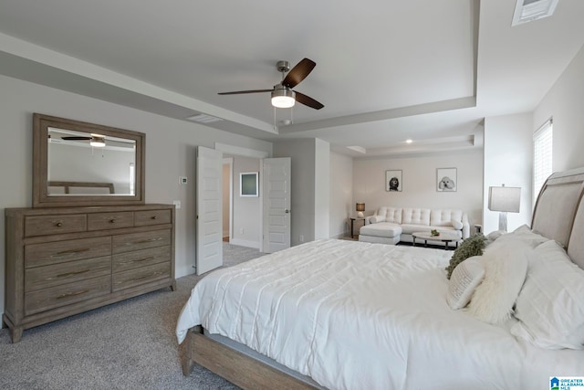 carpeted bedroom featuring a raised ceiling and ceiling fan