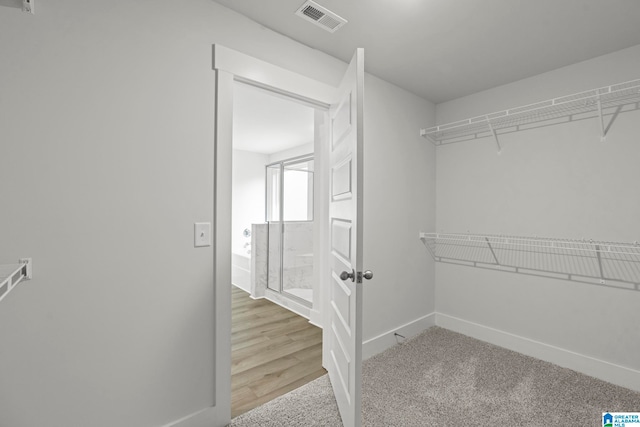 walk in closet with light hardwood / wood-style flooring