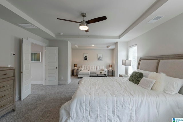 bedroom featuring a raised ceiling, ceiling fan, and light colored carpet